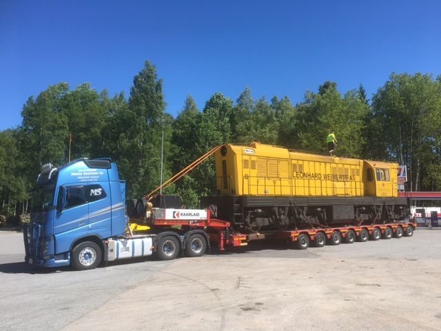 Keltainen veturi monivetoisella lavetilla Volvo FH16:n perässä